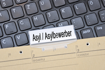 Bild eines Aktenreiters und einer Tastatur - Aufschrift Asylsuchender