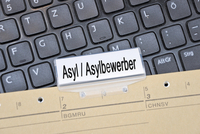 Bild eines Aktenreiters und einer Tastatur - Aufschrift Asylsuchender