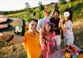 Das Bild zeigt eine Gruppe junger Menschen die sich zu Halloween Kostüme angezogen haben und mit einem Handy ein Foto von sich aufnimmt.