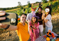 Das Bild zeigt eine Gruppe junger Menschen die sich zu Halloween Kostüme angezogen haben und mit einem Handy ein Foto von sich aufnimmt.